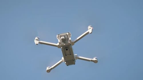 Weiße Drohne hängt in der Luft oder fliegt auf Naturhintergrund. Zeitlupenaufnahme.