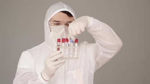 Un investigador masculino con equipo especial está examinando los análisis de sangre