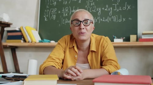 Woman Talking at a Desk in Classroom