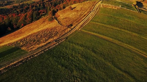 Tourist riding on all-terrain quadricycle vehicle along mountain range in sunset lights.
