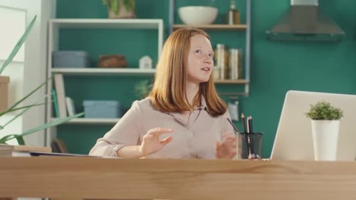 Adolescente pelirroja estudiando en casa en línea viendo un Vídeo tutorial