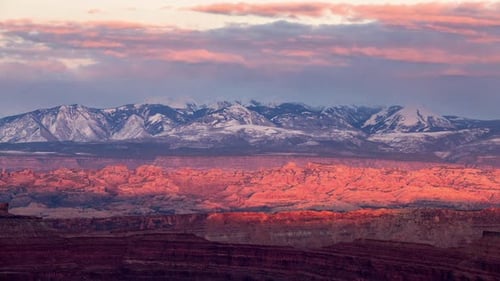Time lapse of sun lighting up cliffs in desert landscape