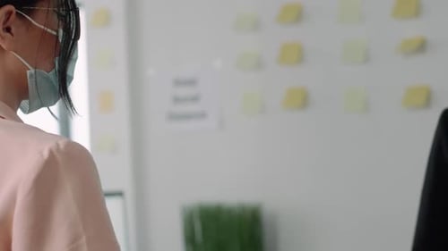 Colleagues Elbow Bumping While Wearing Masks in Office