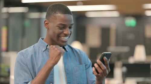 Man Celebrates Success Looking at Mobile Phone