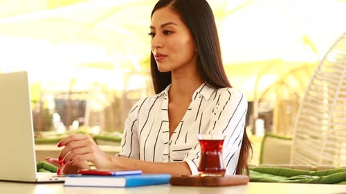 Image of Happy Asian Woman Using Laptop While Sitting at Cafe