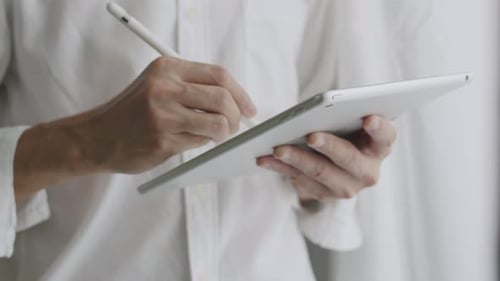 Close-up businessman signing a digital contract on a tablet.