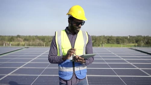 4K afrikanischer Ingenieur verwendet digitales Tablet zur Wartung von Solarzellenmodulen auf dem Dach des Gebäudes.