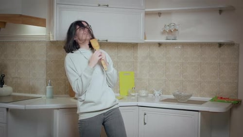 Woman Singing and Dancing with Spoon in Kitchen