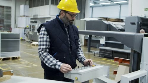 Factory Worker Operating Industrial Machine Control Panel