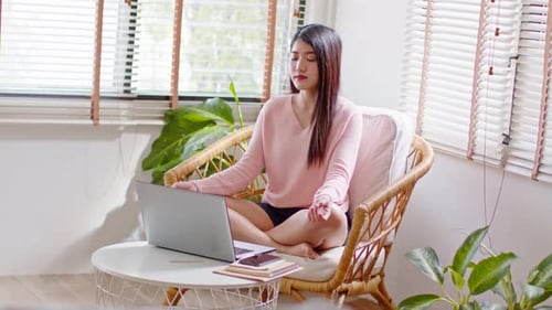 Young Woman Meditating with Laptop in Bright Room