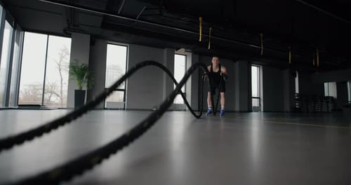 Man Doing Battle Rope Exercise in a Gym