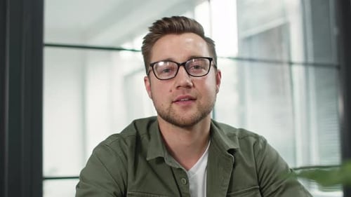 Smiling Man in Green Shirt Sits in Office