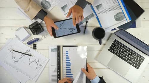 Top View Male Hands of Two Young Businessmen Checking Graphs and Discussing Financial Reports in