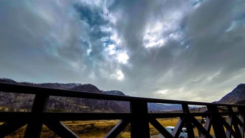 Zeitraffer des Holzzauns auf hoher Terrasse bei Berglandschaft mit Wolken