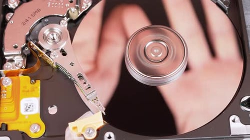 Disque dur à l'intérieur. Reflet des paumes sur la surface miroir d'un disque magnétique