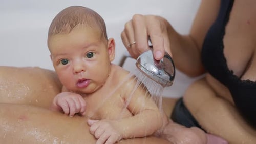 Mother Bathes her Cute Infant with Shower Head