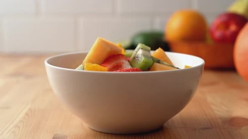 Die Kamera folgt einer Schüssel Obstsalat. Zeitlupe.