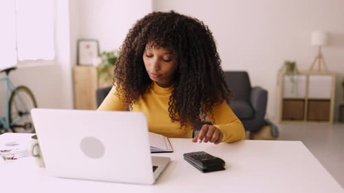 Smiling African American Woman Working with Computer and Calculator at Home