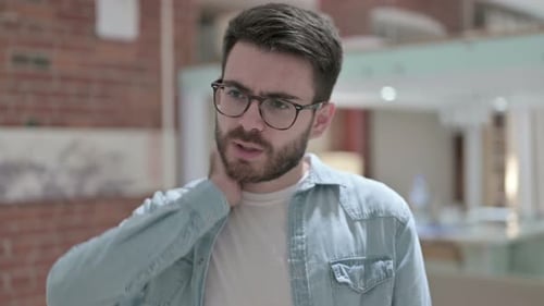 Young Adult Man Rubbing Sore Neck in Pain