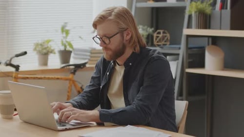 Young Man Working on Laptop in Office