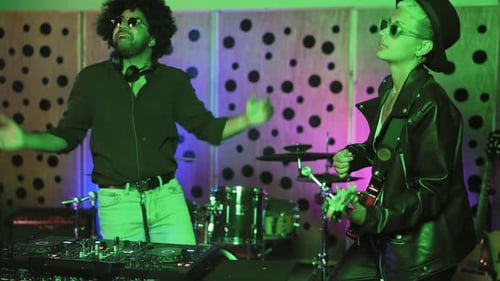 Young happy people playing music with dj mixer and guitar in house studio