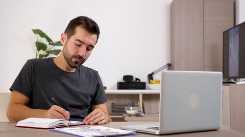 Man writing in notebook at home office
