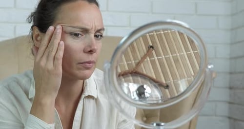 Woman Inspects Face in Mirror Close Up
