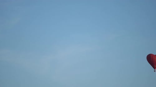 Red Heart Balloon Floats Through Clear Blue Sky