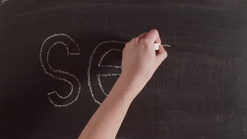 Hand Writes Word 'SEX' on Chalkboard with Chalk