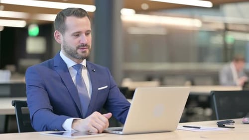 Young Adult Businessman Video Conferencing on Laptop