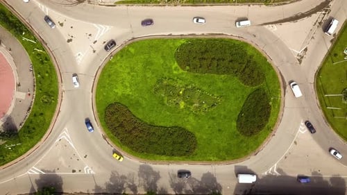 Top down aerial view of roundabout street intersection with moving cars traffic.