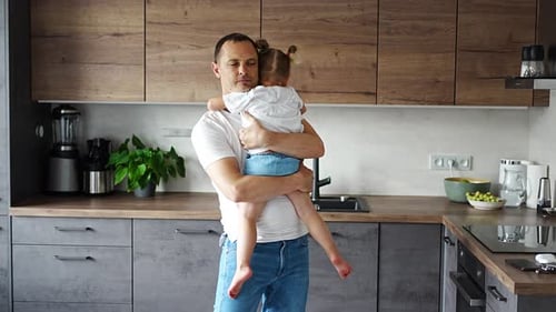 Affectionate Father Holding His Young Daughter in Kitchen