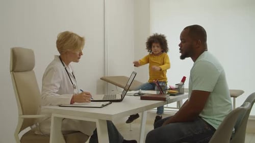 Doctor Talking with Child and Father in Office