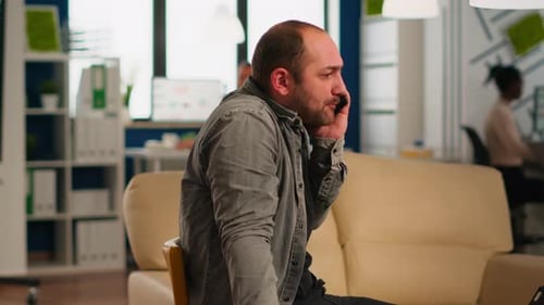 Man Sits Talking on the Phone in Office