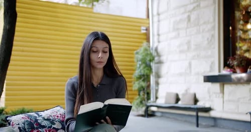 Woman Reads a Book Sitting Outdoors