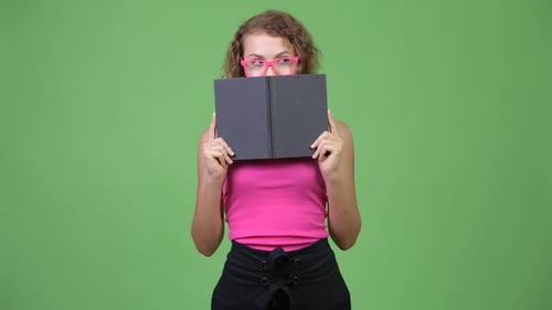 Jeune femme nerd timide aux cheveux blonds bouclés se cachant derrière un livre