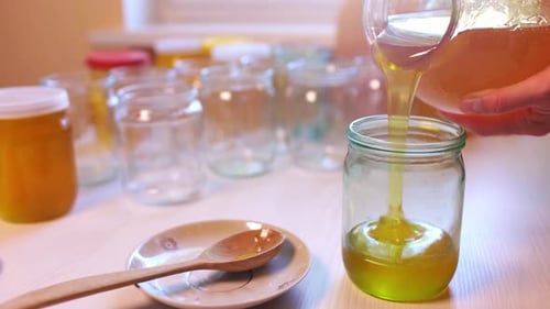 Pouring Sweet Honey into Glass Jar