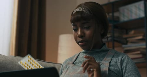 Woman Discusses Pills During Telehealth Appointment at Home