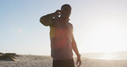 Man at Beach Using Wireless Headphones and Smartwatch