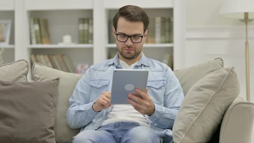 Young Adult Using Tablet While Relaxing on Sofa