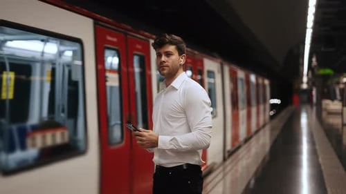 Man Using Phone on Subway Platform at Night
