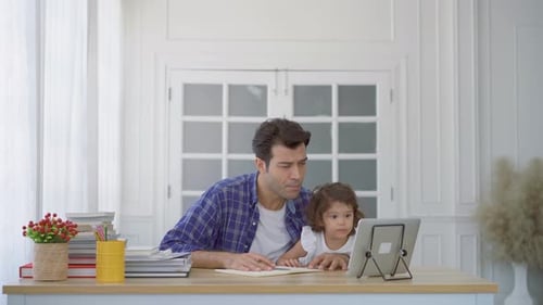 Padre y pequeña hija linda viendo el vídeo tutorial en la tableta y enseñando los deberes