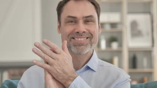 Man Smiling and Clapping in Home Setting