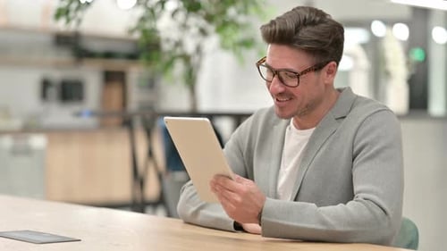 Man on Tablet Video Call in Modern Office