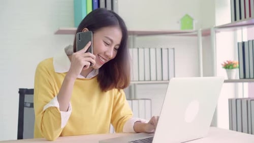 Woman Works and Talks on Phone at Desk