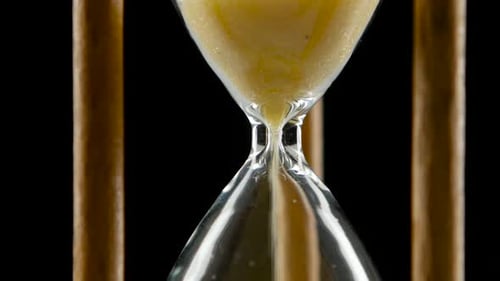 Sand Falls Through a Bottleneck in a Hourglass. Black. Close Up