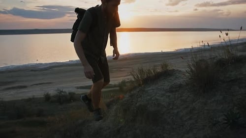 Joven fotógrafo con mochila está subiendo en High Hill