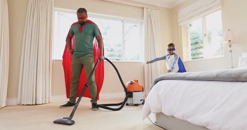 Dad and Son Superheroes Vacuuming in Bedroom
