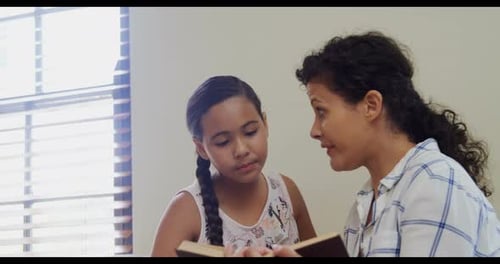 Woman Reads Book Aloud to Child at Home
