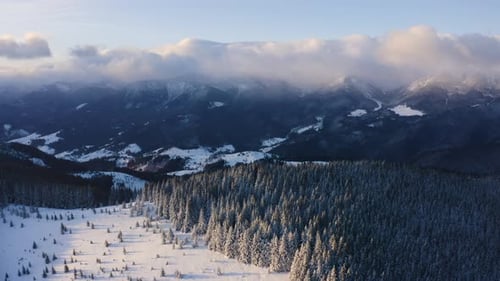 Aerial Top Down Flyover Shot of Winter Mountain Covered with Snow and Clouds